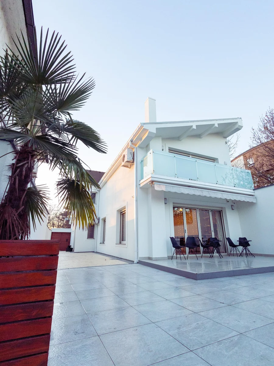 Modern white house exterior with palm trees and an open patio