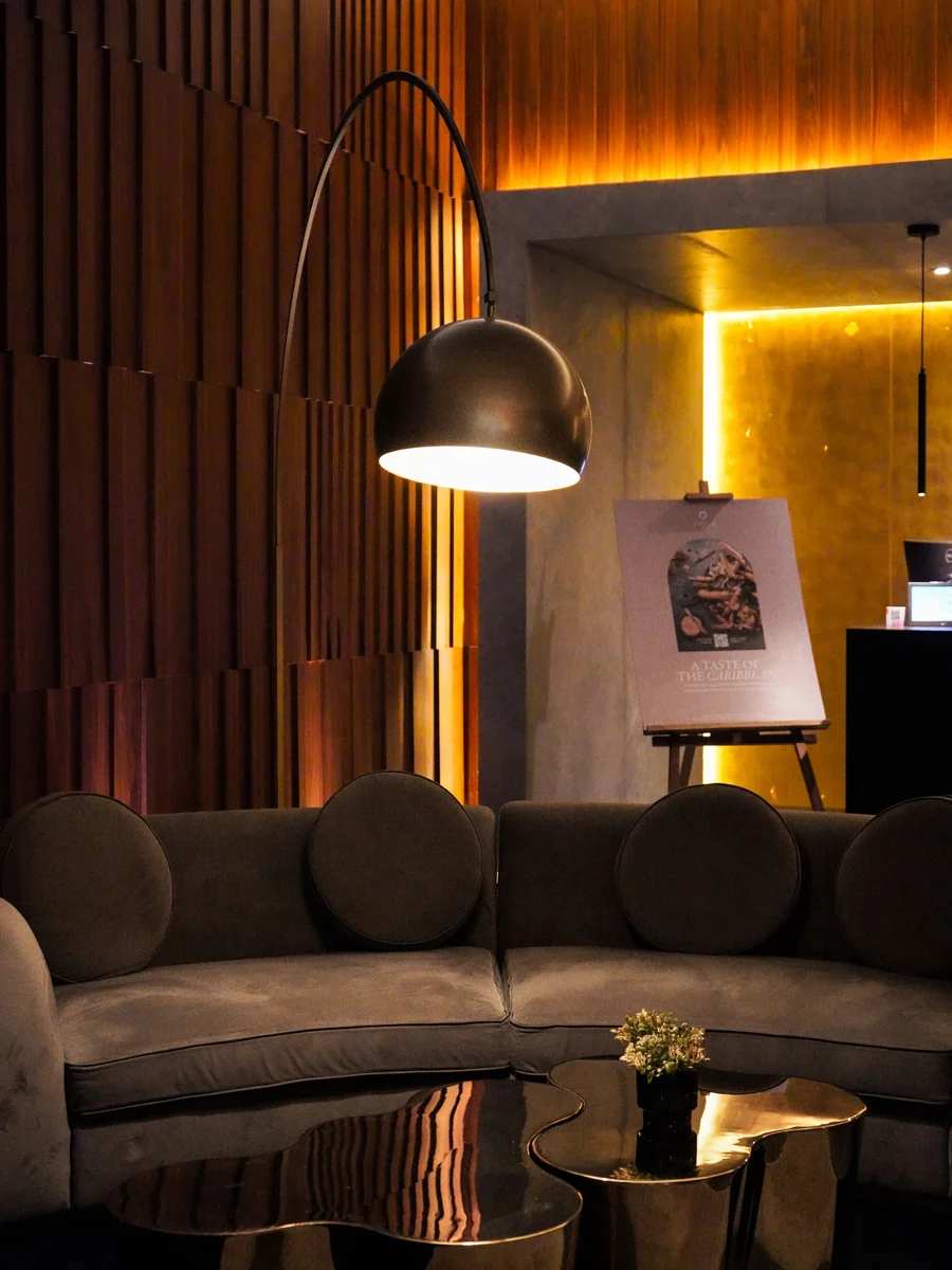 Warmly lit modern lounge with a curved sofa and standing lamp