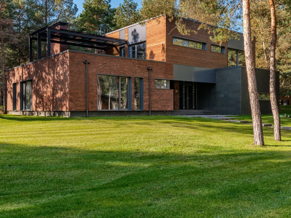 House with wide glass frontage surrounded by mature trees