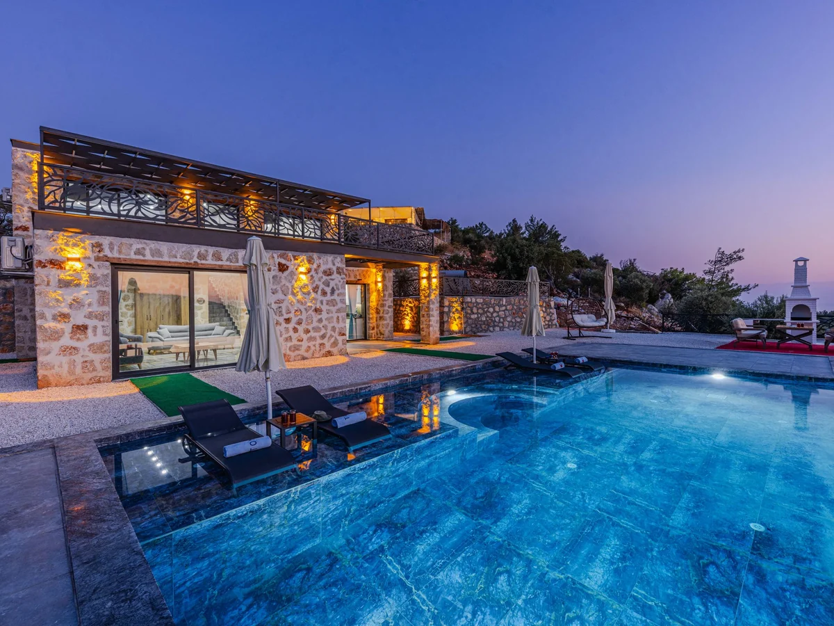 Stone villa with an infinity pool lit at twilight