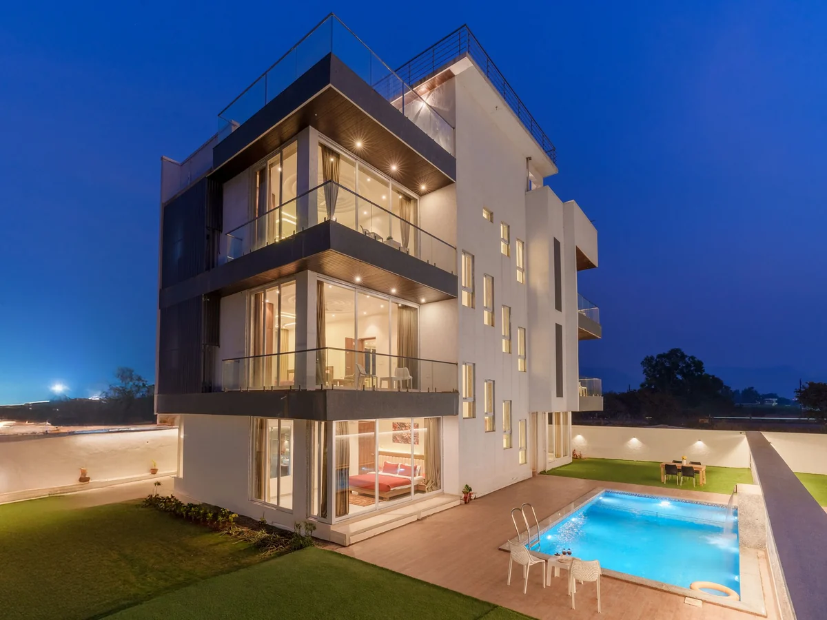 Modern luxury villa with a lit pool at twilight